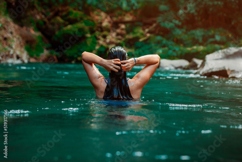 young Latina woman swimming in Rio Fortuna in Costa Rica with totally wet long hair