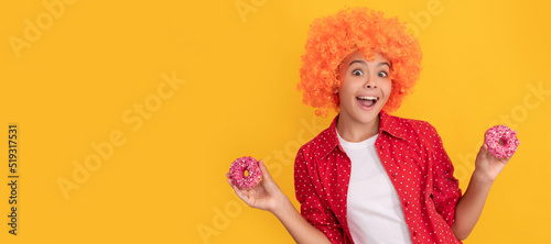 surprised kid in fancy orange wig hair hold sweet glazed donut, surprise. Teenager child with sweets, poster banner header, copy space.