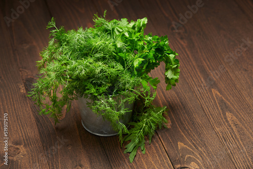 a bunch of green dill and parsley in an iron bucket, dark wooden background, concept of fresh vegetables and healthy food
