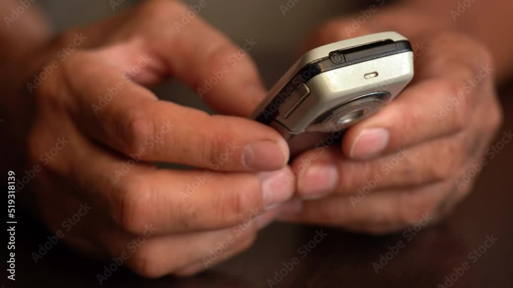 A button phone in the wrinkled hands of an elderly person A button phone in the wrinkled hands of an elderly person