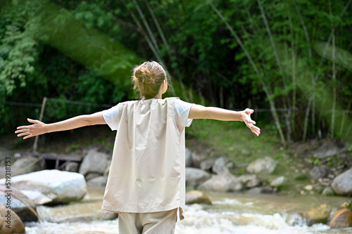 Relaxed Asian female traveler standing with carefree pose near the river and getting fresh air.