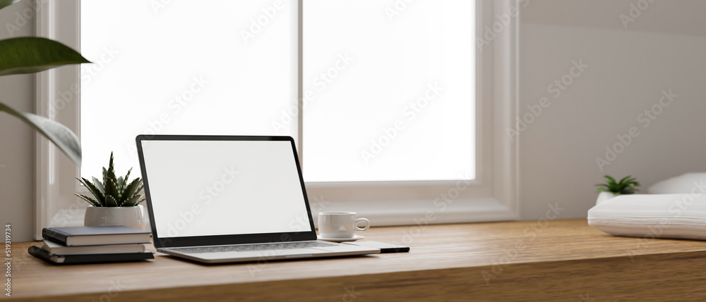 Minimal and comfortable home working space with laptop on wood tabletop against the window. Minimal and comfortable home working space with laptop on wood tabletop against the window.