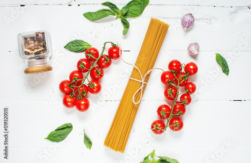 Spaghetti, basil and tomatoes isolated on white wooden table. Top view