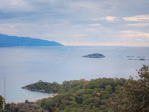 travel to Lagoon in Oludeniz, Fethiye, Turkey. beach near Darbogaz. Winter landscape with mountains, green forest, azure water, beach and cloudy sky