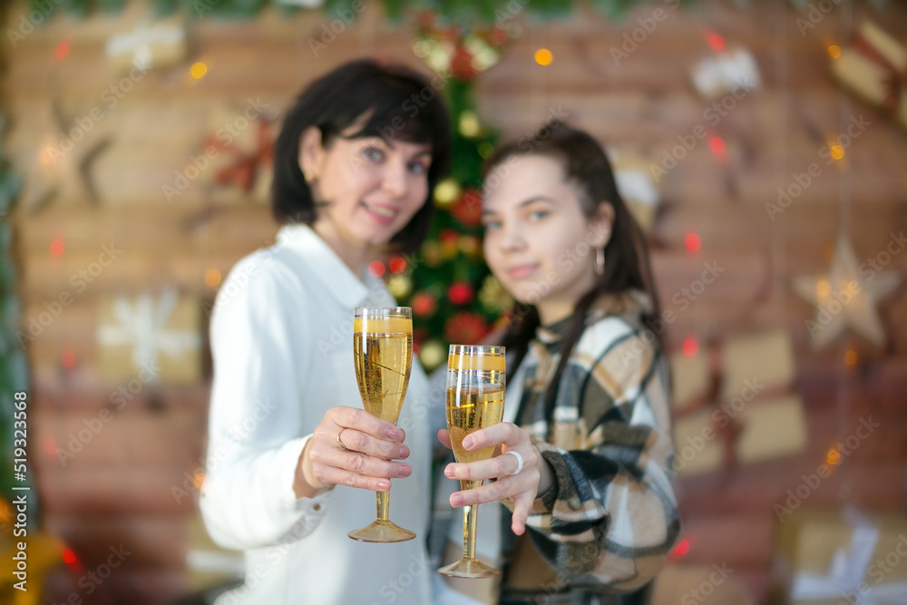 Mom and adult daughter with glasses of champagne celebrate new year,