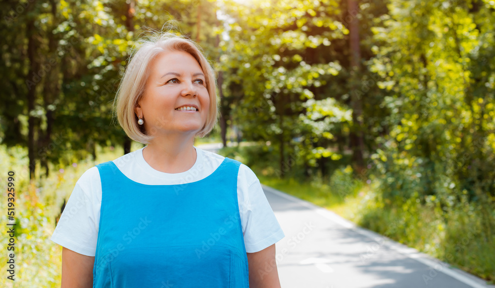Portrait of happy senior woman relaxing and breathing fresh air with sunlight in outdoors park. Elderly woman enjoying a day in the park on summer.