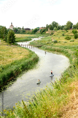 People paddle boarding at the river in summer day © Gioia