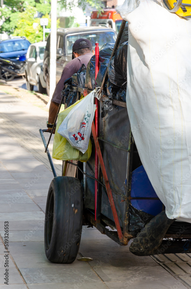 homeless man carrying garbage sacks on a cart homeless man carrying garbage sacks on a cart