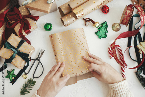 Konstfotografi Merry Christmas! Hands wrapping stylish christmas gifts flat lay