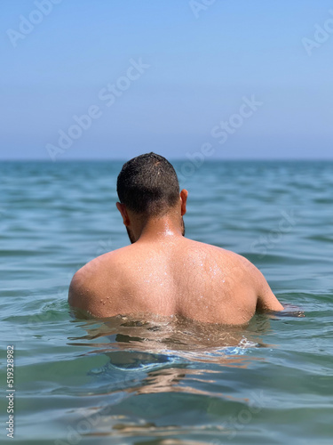 Muscular man standing alone in the middle of the sea