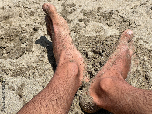 Closeup of male feet covered with sand on the beach