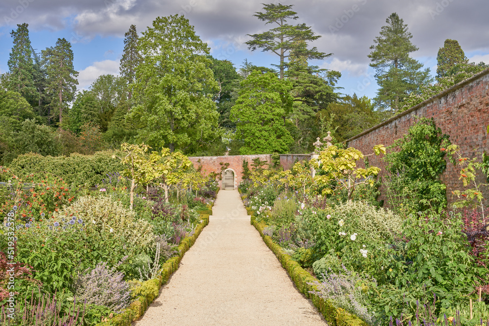 Walled garden with gravel path and traditional herbacious perennial planting in summer