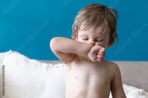 Photography Cute little toddler boy rubs and scratches his nose with hand sitting at home