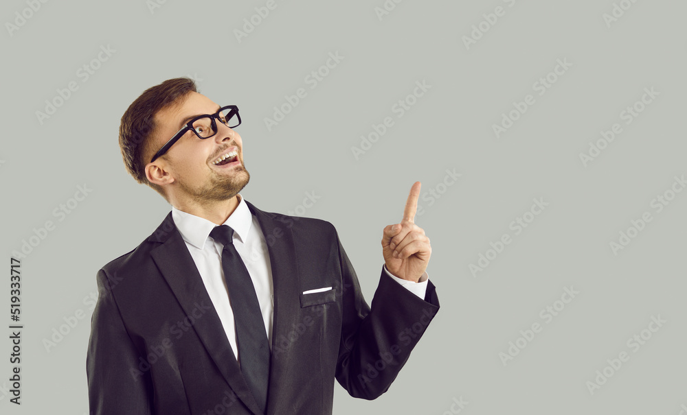Funny crazy looking entrepreneur thinks of a great, brilliant business idea. Studio portrait of a happy cheerful man isolated on a solid light gray background smiling and pointing his index finger up Funny crazy looking entrepreneur thinks of a great, brilliant business idea. Studio portrait of a happy cheerful man isolated on a solid light gray background smiling and pointing his index finger up