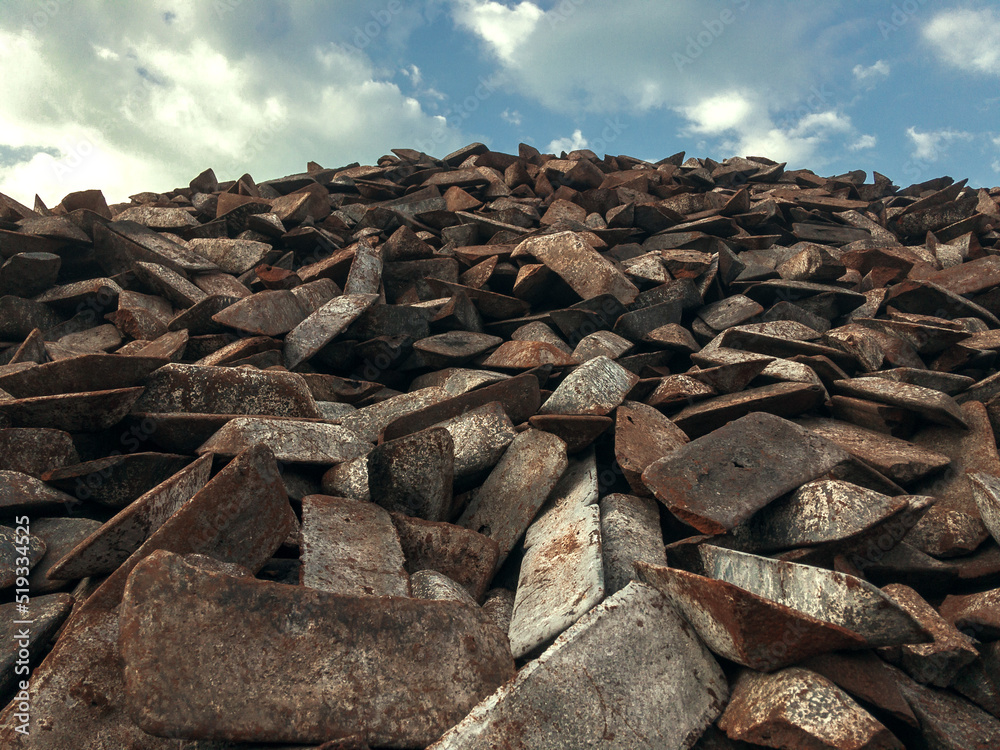 Cast iron ingots in a warehouse against a blue sky. The form of