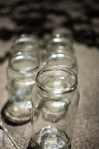 Various size and shape empty glass jars with no lids, set on the ground pavement, no people, close up shot