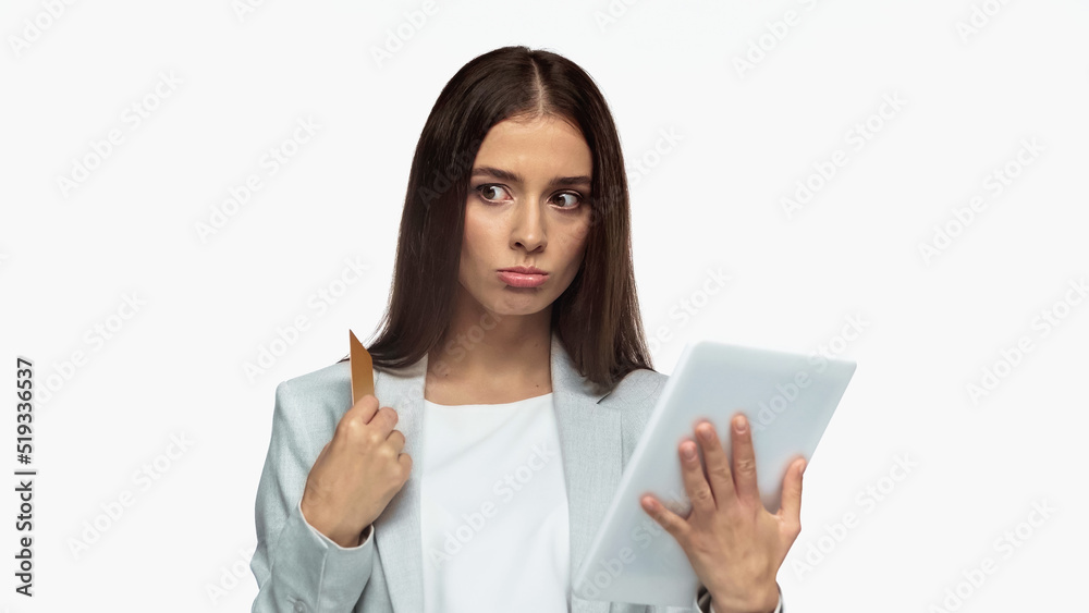 pensive businesswoman in grey blazer holding credit card and digital tablet isolated on white. pensive businesswoman in grey blazer holding credit card and digital tablet isolated on white.