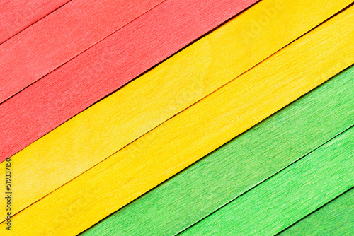 Textured wooden boards in traffic light colors. The wooden boards are painted red, yellow and green and arranged diagonally. Wooden detailed background in three colors.