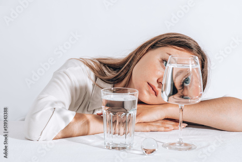 Casual style young woman posing on studio background, hold water glass. Beautiful girl portrait. Female model poses.