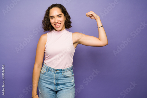 Powerful woman laughing and feeling strong while showing her bicep © AntonioDiaz