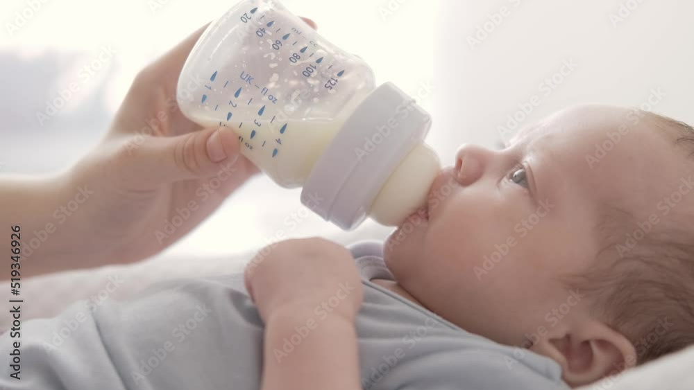 loving mother feeding her little boy child with milk baby bottle at home, portrait infant Baby eating, drinking powdered milk loving mother feeding her little boy child with milk baby bottle at home, portrait infant Baby eating, drinking powdered milk