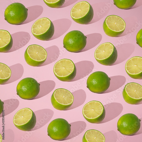 Pattern with limes in vibrant green color. Green colors and shadows on a soft pink background. Healthy, organic, vitamin lifestyle. Refreshing food  fruit concept idea. Citrus party design