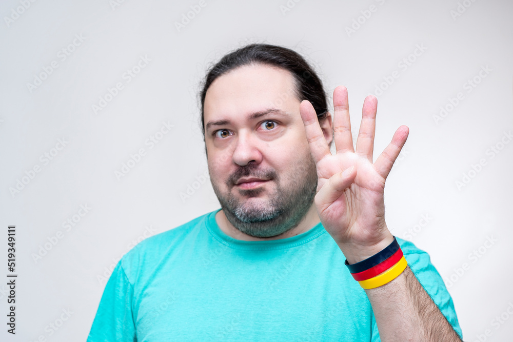 An adult man shows the number four with his fingers. Four outstretched fingers. Bracelet in the colors of the German flag.