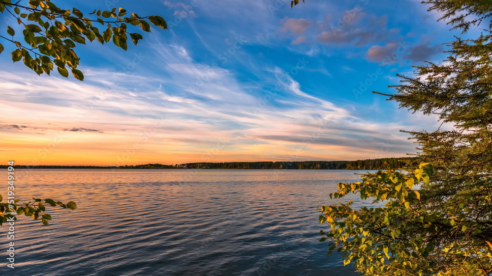 Sunset over a blue lake with green trees on the shore