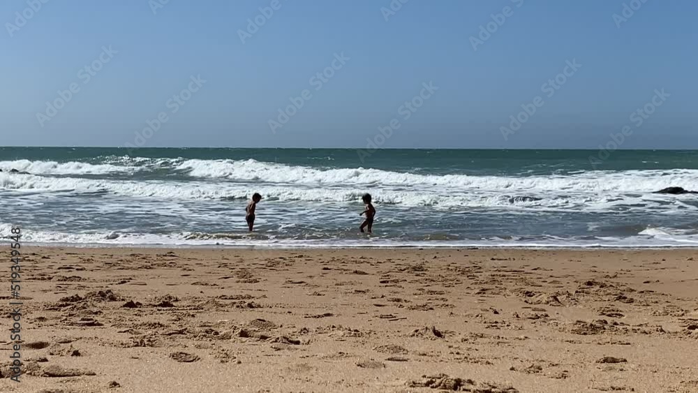Small children playing, running, laughing, jumping in puddles on the wonderful Roche beach, in Cádiz, Spain