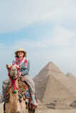  tourist woman riding a dromedary in front of pyramids. Egypt, Cairo - Giza