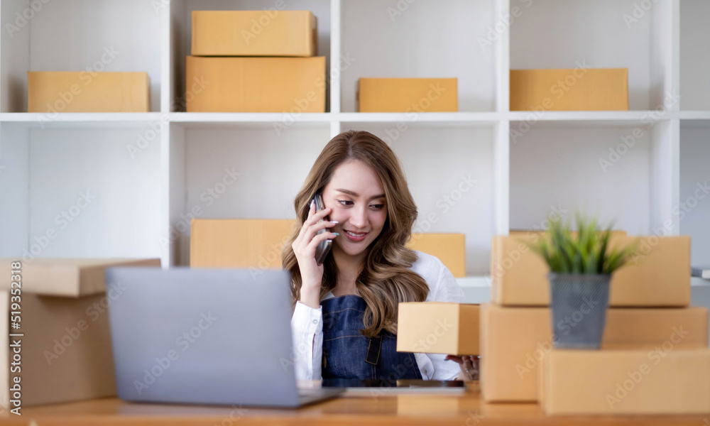 Portrait of young asian business woman talk on smartphone write notebook laptop in home office. Beautiful girl at desk computer take home order. Startup business asia woman online sme telemarketing. Portrait of young asian business woman talk on smartphone write notebook laptop in home office. Beautiful girl at desk computer take home order. Startup business asia woman online sme telemarketing.
