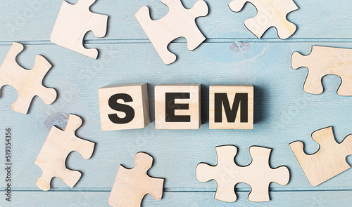 Blank puzzles and wooden cubes with the text SEM Search Engine Marketing lie on a light blue background.