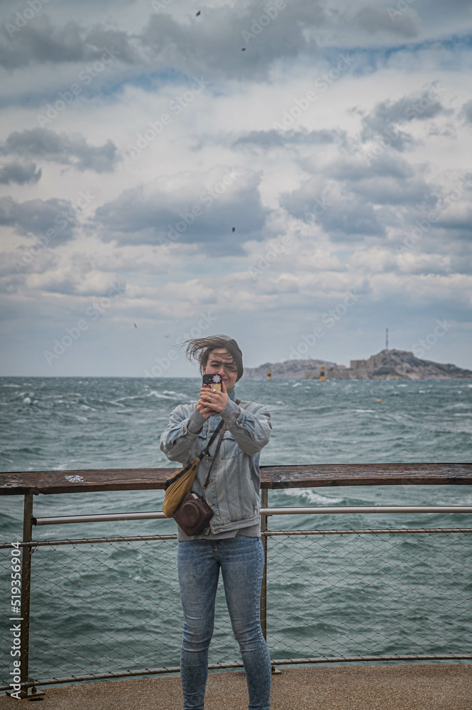 junge Frau bei stürmischen Wetter auf Aussichtsplattform über Meer