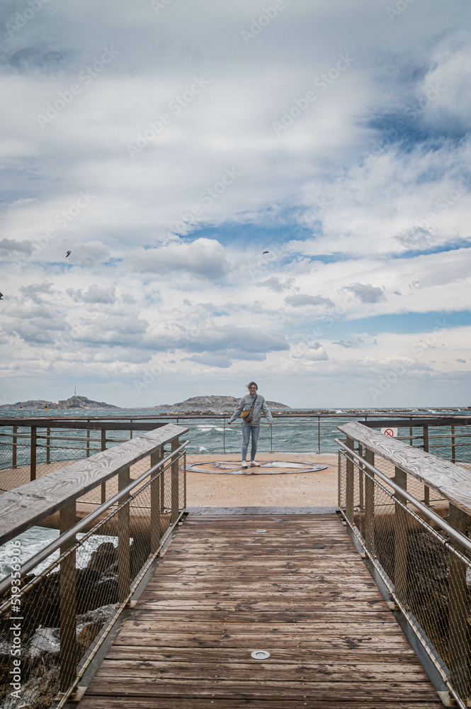 junge Frau bei stürmischen Wetter auf Aussichtsplattform über Meer
