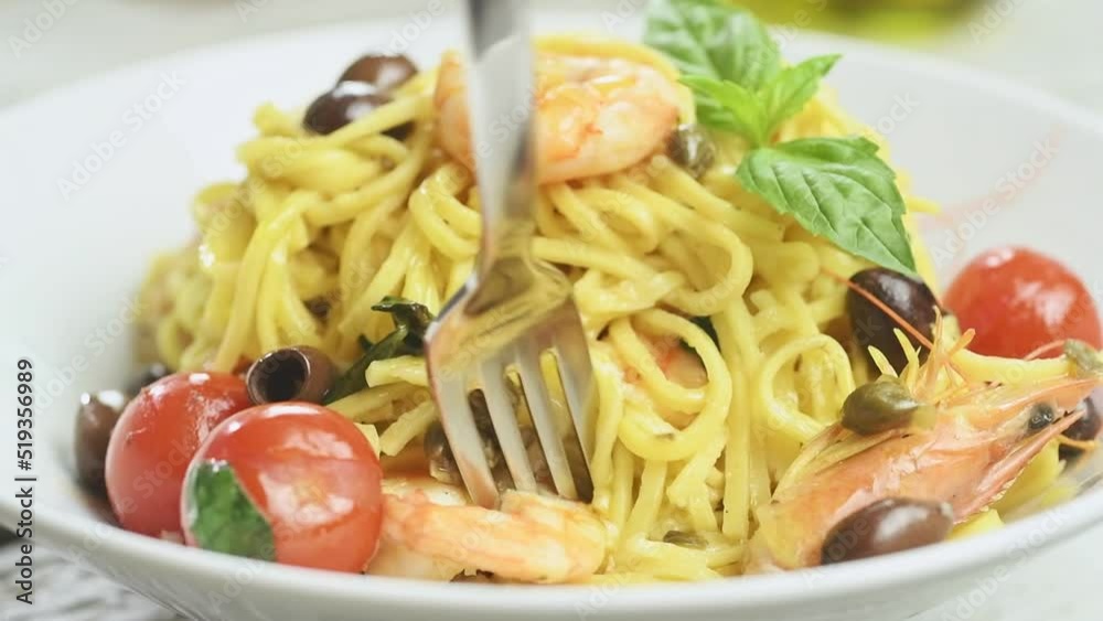 Eating spaghetti with shrimp and cherry tomatoes.
