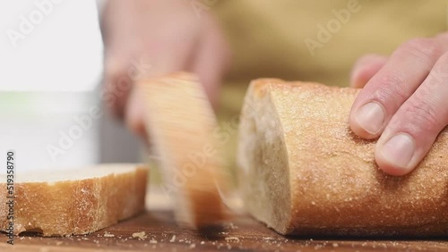 Slicing ciabatta bread on cutting board, slow motion.
 photo