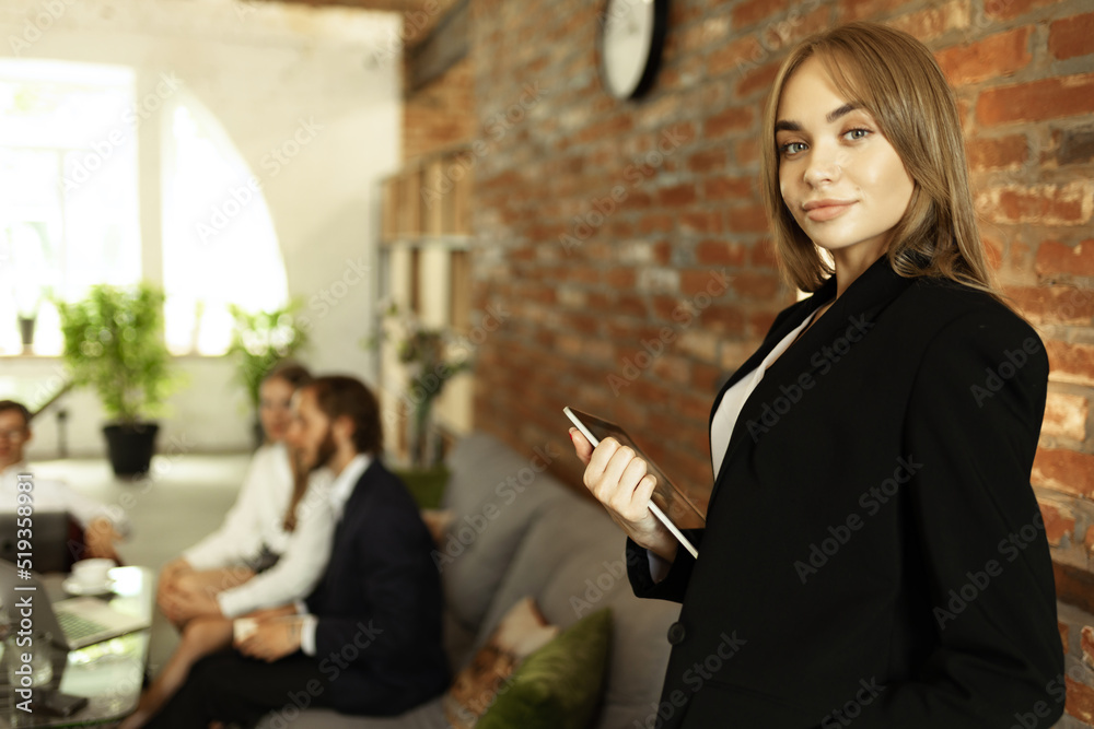 Portrait of young woman, office manager, employee in official suit working at modern work studio. Making project presentation Portrait of young woman, office manager, employee in official suit working at modern work studio. Making project presentation