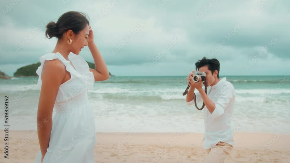 Happy young couple wearing white dress enjoy taking photo on the beach on holidays, travel, romantic, wedding concept Happy young couple wearing white dress enjoy taking photo on the beach on holidays, travel, romantic, wedding concept
