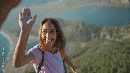 Couple hiking in Turkey, POV slow motion woman hiker rock climber climbs up on cliff on mountain over beautiful sea beach Iztuzu in Turkey and gives high five for teammate. successful ascent