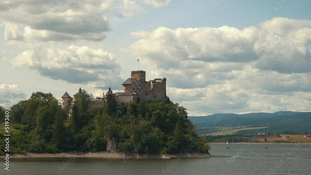 Niedzica Castle Also Known as Dunajec Castle by Lake Czorsztynin the Pieniny Mountains, Poland. And Tourist Ferrys in the Lake. Summer Day With Fast Moving Clouds. Niedzica Castle Also Known as Dunajec Castle by Lake Czorsztynin the Pieniny Mountains, Poland. And Tourist Ferrys in the Lake. Summer Day With Fast Moving Clouds.