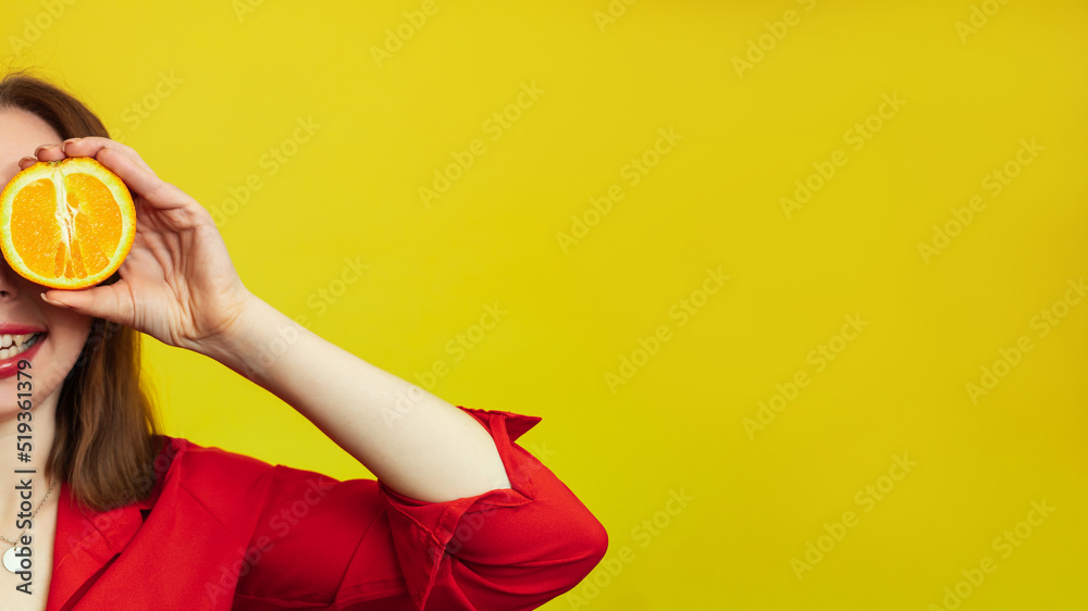 Portrait of a Caucasian girl with a radiant clean skin holding orange halves isolated on a yellow background. The concept of cosmetics with vitamin C. A place for your advertising or text.