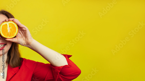 Portrait of a Caucasian girl with a radiant clean skin holding orange halves isolated on a yellow background. The concept of cosmetics with vitamin C. A place for your advertising or text.