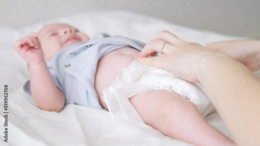 Mother changes diapers to her newborn baby, Little boy on changing table in clean dry nappy, Mom taking care of infant child, motherhood daily routine
