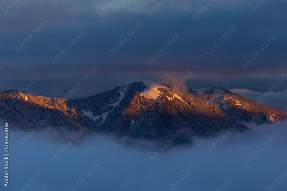 Colorful winter sunset in the Alps, above the inversion and clouds