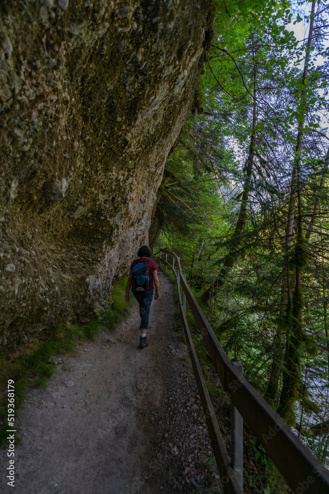 Wanderin in der Bürserschlucht, wandernde Frau neben den steilen Felswänden auf dem schmalen Weg durch die bewaldete Schlucht. bei Bürs in Vorarlberg, Österreich