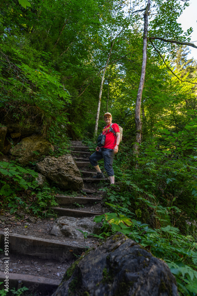 Obraz premium Wanderer auf dem Weg durch die Bürser Schlucht, Mann auf dem schmalen Wanderweg über Treppen und Stufen durch die bewaldete Schlucht bei Bürs, Vorarlberg, Österreich