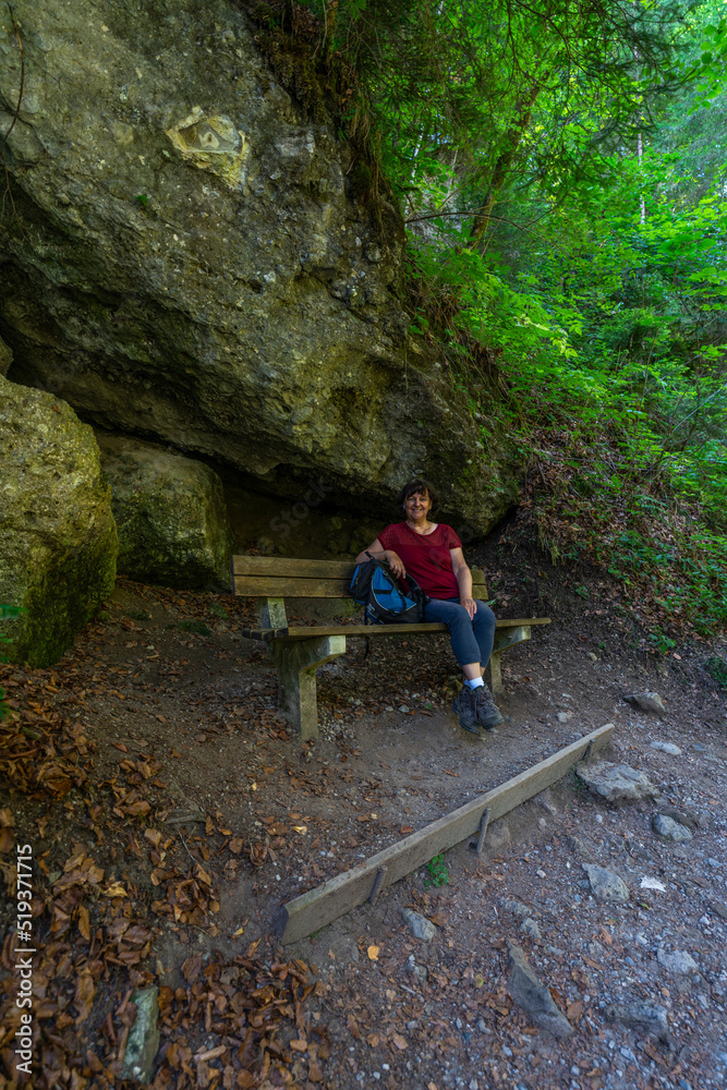 Obraz premium Wanderin in der Bürserschlucht, wandernde Frau neben den steilen Felswänden auf dem schmalen Weg durch die bewaldete Schlucht. bei Bürs in Vorarlberg, Österreich