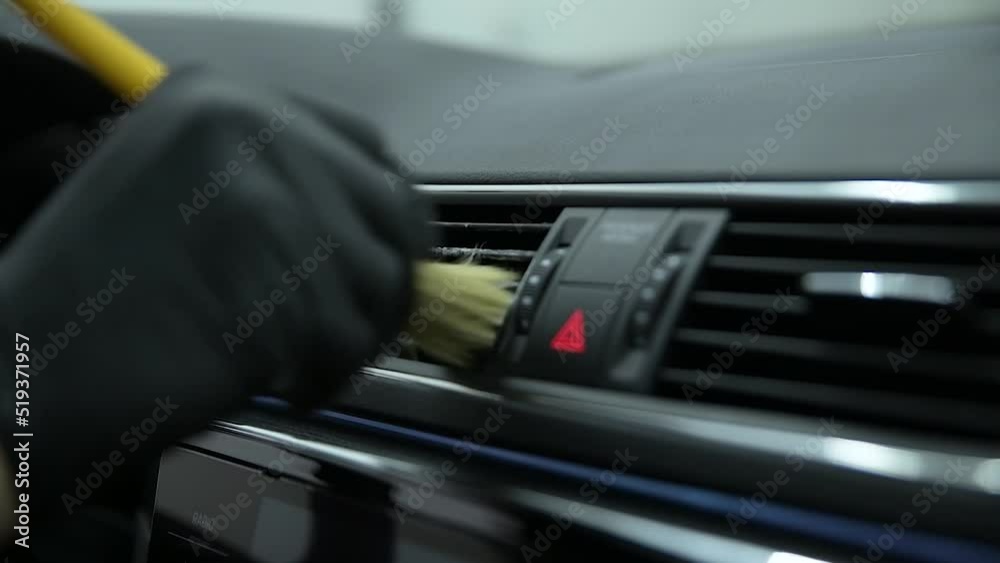 Car wash or car detailing studio employee wash the air vents in the car with a brush Car wash or car detailing studio employee wash the air vents in the car with a brush