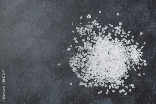 Photos Sea salt in wooden bowl on black table.