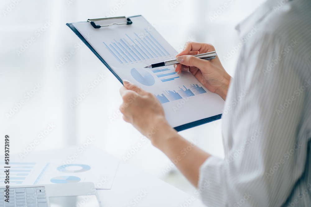 Young businesswoman analyzes cost graphs on desk in conference room with laptop Young businesswoman analyzes cost graphs on desk in conference room with laptop